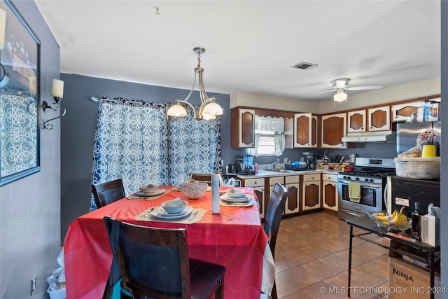 1421 S Hayes Ave, Wagoner, OK 74467 - kitchen with gas range, under cabinet range hood, a ceiling fan, dark tile patterned flooring, and pendant lighting