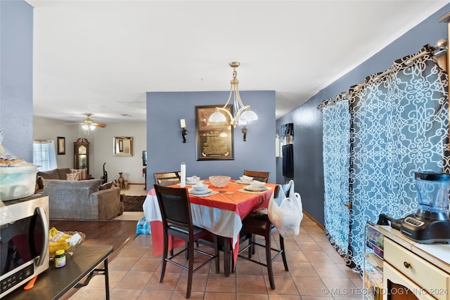 tiled dining area featuring ceiling fan with notable chandelier