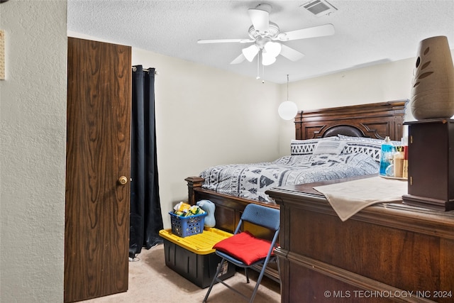 bedroom featuring ceiling fan, light carpet, and a textured ceiling