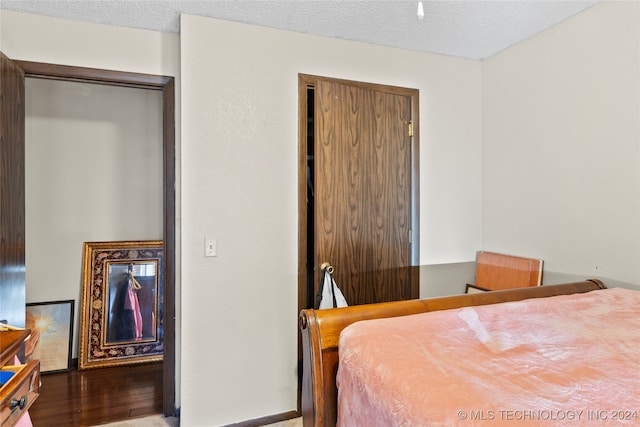 bedroom with a closet, a textured ceiling, and wood-type flooring