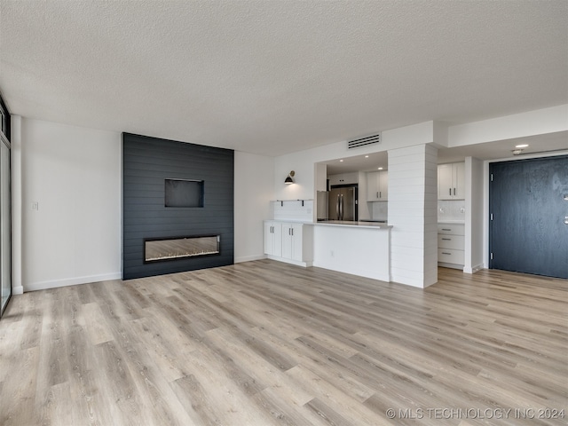 unfurnished living room featuring a textured ceiling, light hardwood / wood-style flooring, and a fireplace