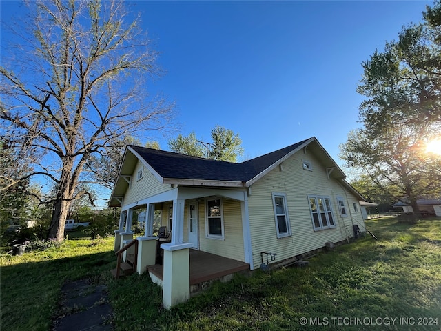 view of side of home with a porch and a lawn