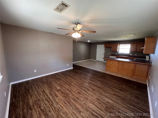 kitchen with ceiling fan, sink, dark wood-type flooring, and kitchen peninsula