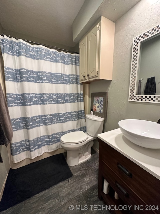 bathroom with vanity, curtained shower, a textured ceiling, hardwood / wood-style flooring, and toilet