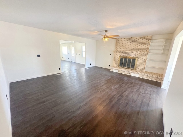 unfurnished living room featuring ceiling fan, a fireplace, dark hardwood / wood-style floors, and built in features