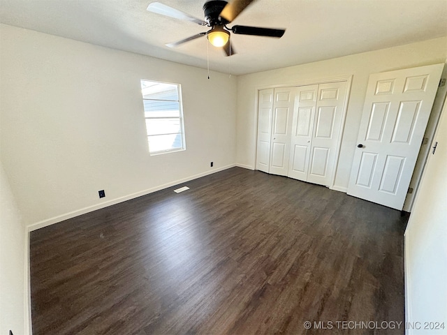 unfurnished bedroom featuring dark hardwood / wood-style floors, ceiling fan, and a closet