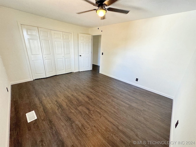 unfurnished bedroom featuring a closet, ceiling fan, and dark wood-type flooring