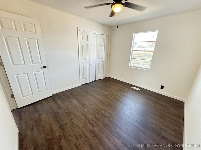 unfurnished bedroom with a closet, ceiling fan, and dark hardwood / wood-style flooring