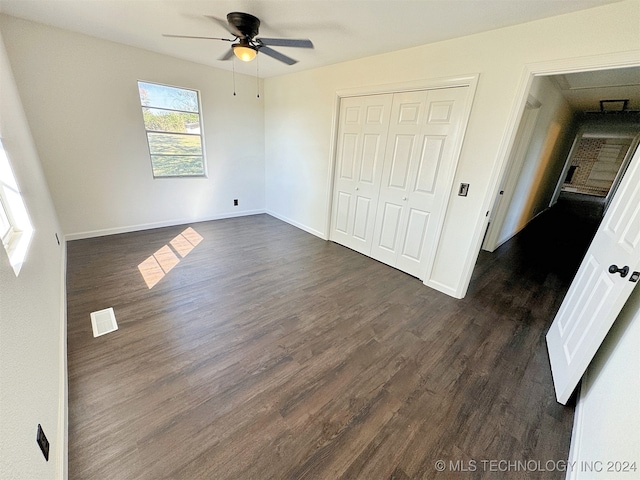 unfurnished bedroom featuring ceiling fan, a closet, and dark wood-type flooring