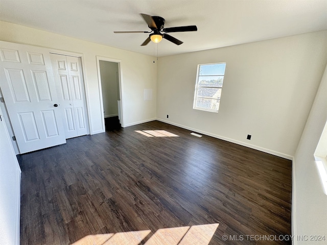 unfurnished bedroom with ceiling fan, a closet, and dark wood-type flooring