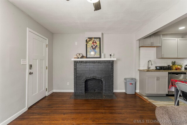 living room with baseboards, a brick fireplace, wood finished floors, and a ceiling fan