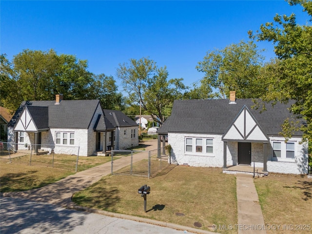 tudor-style house with a front lawn, fence, and a chimney