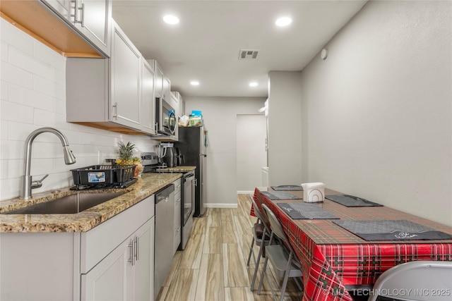 kitchen featuring visible vents, a sink, tasteful backsplash, white cabinetry, and appliances with stainless steel finishes