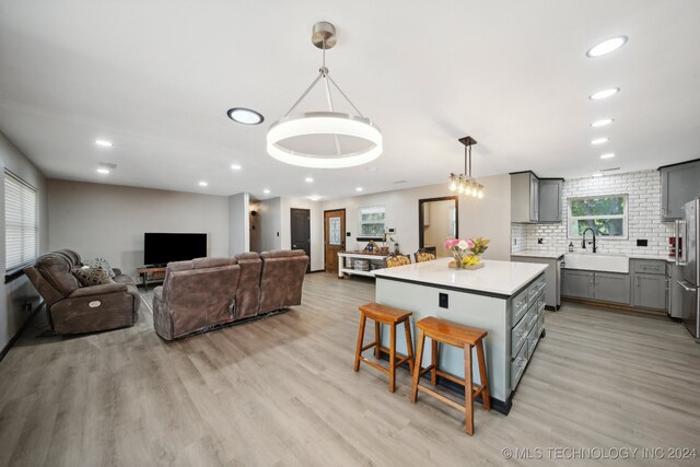 kitchen featuring sink, hanging light fixtures, a kitchen breakfast bar, gray cabinets, and a kitchen island