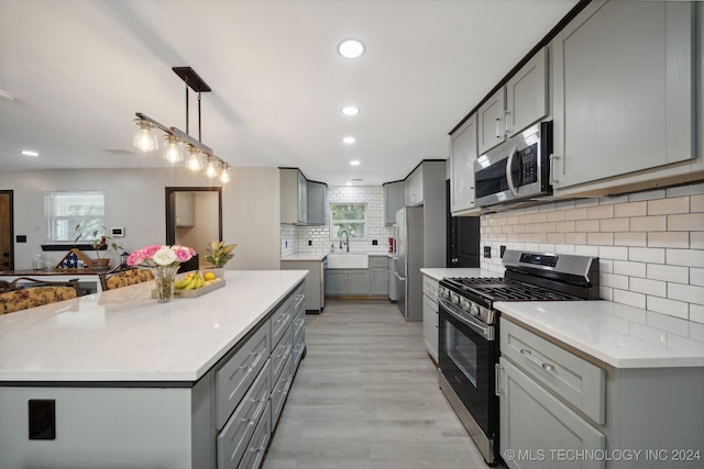 kitchen with sink, gray cabinets, stainless steel appliances, decorative backsplash, and decorative light fixtures