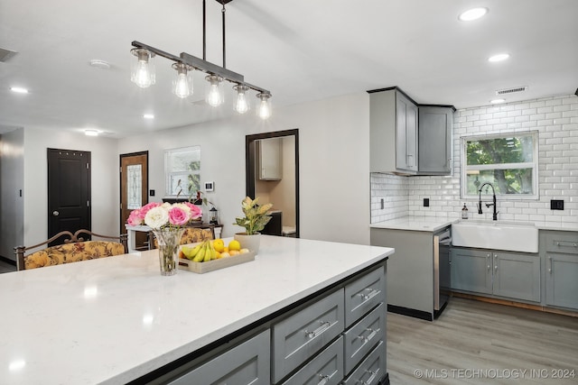 kitchen featuring pendant lighting, sink, gray cabinetry, tasteful backsplash, and light hardwood / wood-style floors