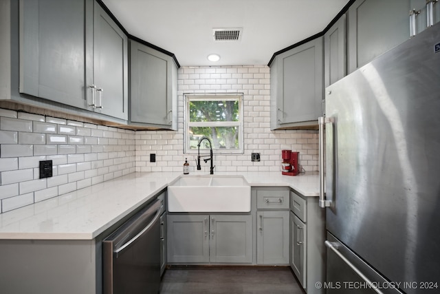 kitchen featuring gray cabinets, appliances with stainless steel finishes, tasteful backsplash, sink, and light stone countertops