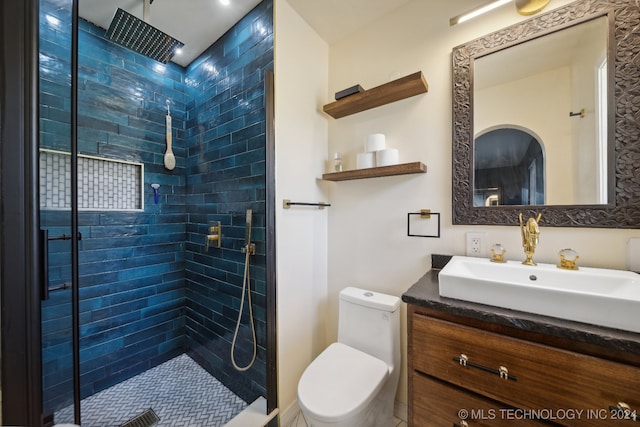 bathroom with vanity, toilet, and tiled shower