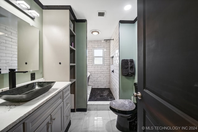 bathroom featuring tiled shower, ornamental molding, and vanity