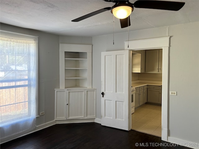 unfurnished dining area featuring ceiling fan, dark wood-type flooring, and a textured ceiling