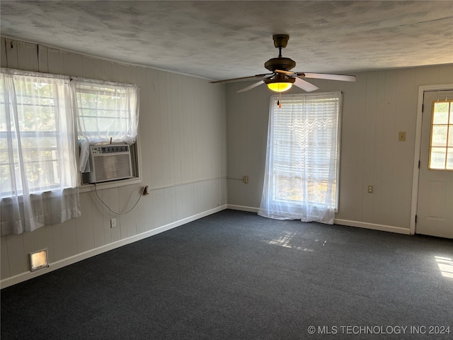 carpeted empty room with cooling unit, ceiling fan, and wooden walls