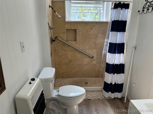 bathroom with wood walls, wood-type flooring, heating unit, walk in shower, and toilet