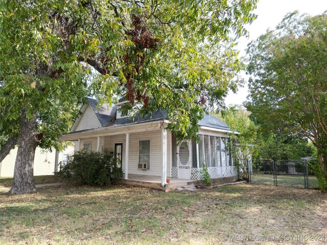 view of front facade with a porch, a front yard, and cooling unit