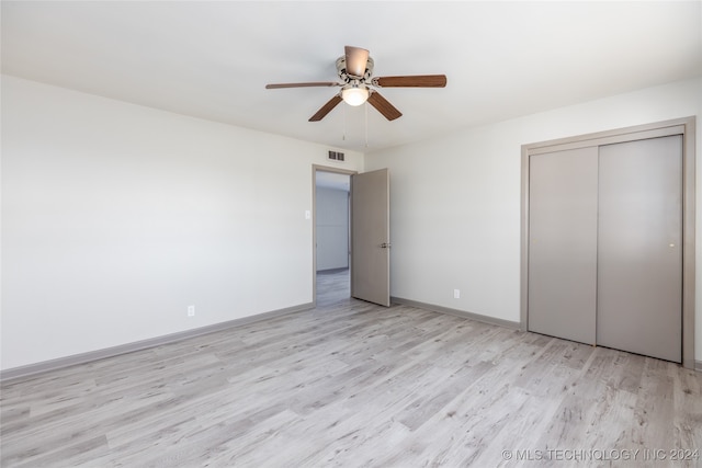 unfurnished bedroom with light wood-type flooring, ceiling fan, and a closet