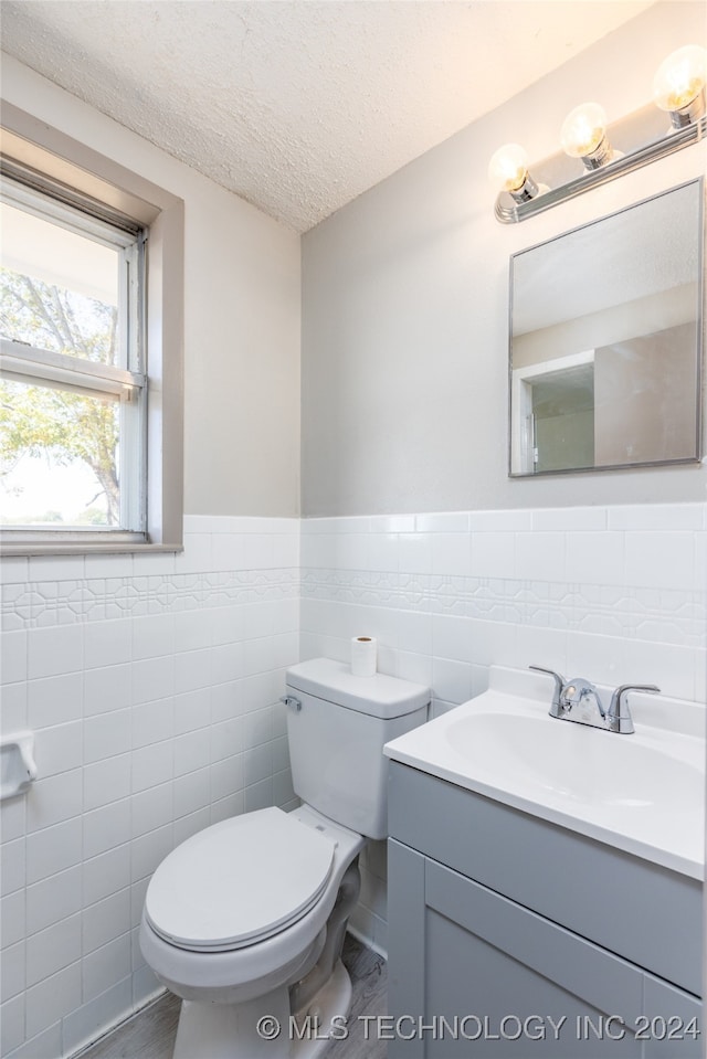 bathroom with tile walls, a textured ceiling, vanity, and toilet