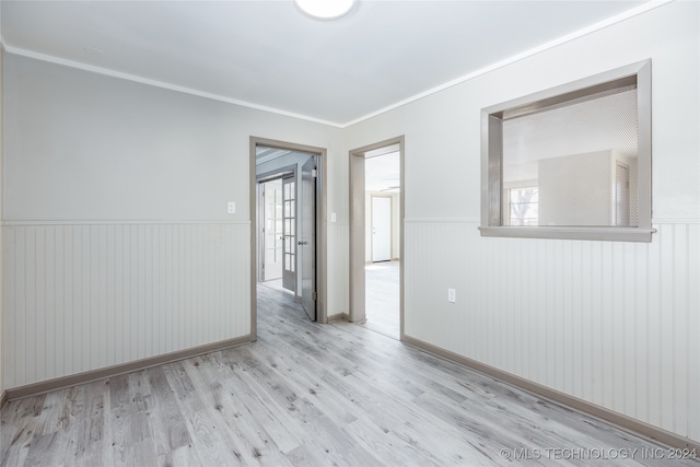 empty room featuring wooden walls, light hardwood / wood-style floors, and ornamental molding