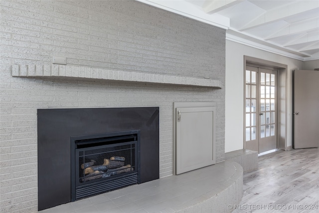 interior details with wood-type flooring, white refrigerator, beam ceiling, a large fireplace, and french doors