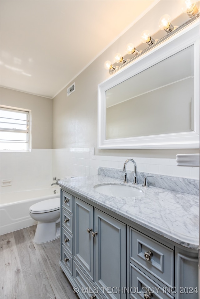 bathroom featuring a bathing tub, hardwood / wood-style flooring, vanity, and toilet