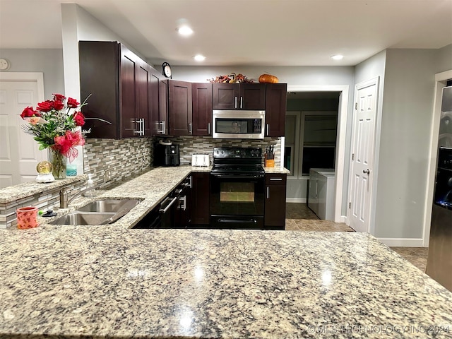 kitchen with sink, tasteful backsplash, black / electric stove, washing machine and dryer, and light stone countertops