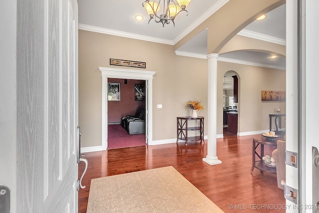 entrance foyer with ornamental molding, an inviting chandelier, ornate columns, and dark hardwood / wood-style flooring