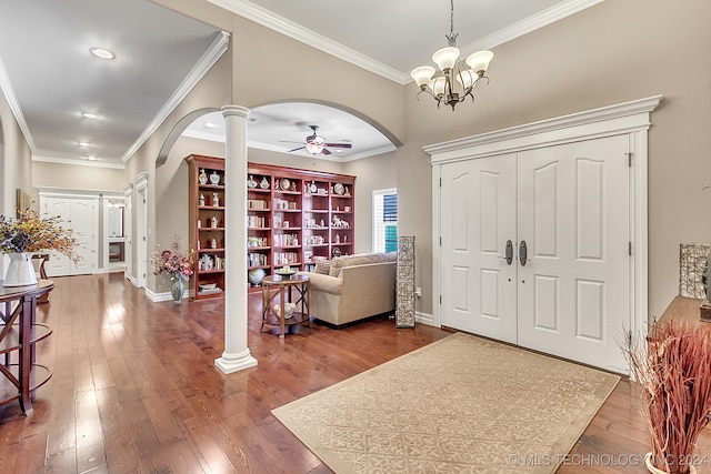 foyer entrance with ceiling fan with notable chandelier, decorative columns, ornamental molding, and dark hardwood / wood-style flooring