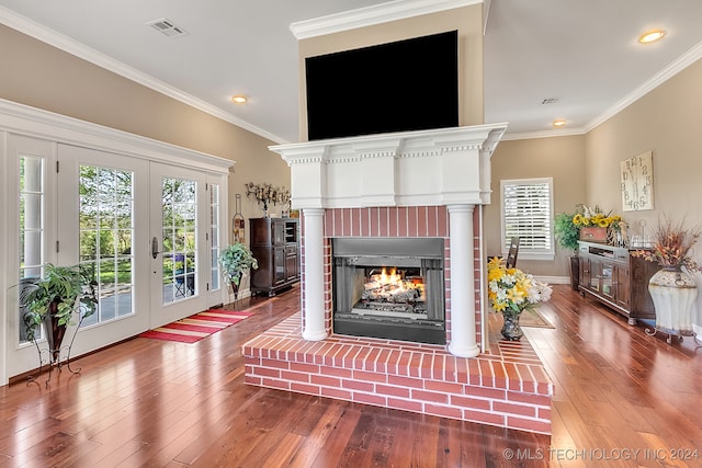 living room with french doors, wood-type flooring, a fireplace, and crown molding