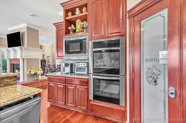 kitchen featuring stainless steel appliances, crown molding, light wood-type flooring, and tasteful backsplash