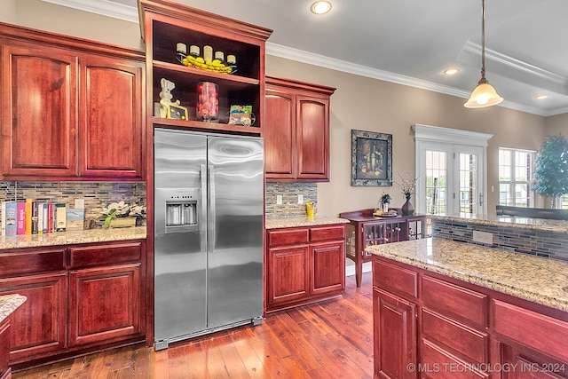 kitchen with hanging light fixtures, backsplash, dark hardwood / wood-style flooring, crown molding, and built in fridge