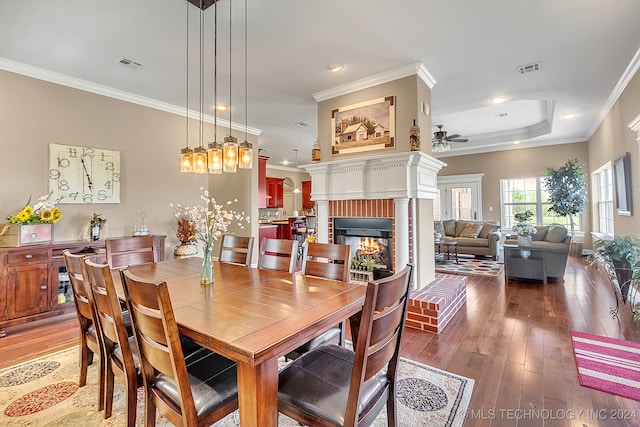 dining space with ceiling fan, ornamental molding, a fireplace, and hardwood / wood-style floors