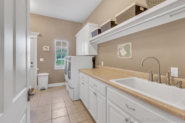 clothes washing area featuring washing machine and clothes dryer, cabinets, light tile patterned floors, and sink