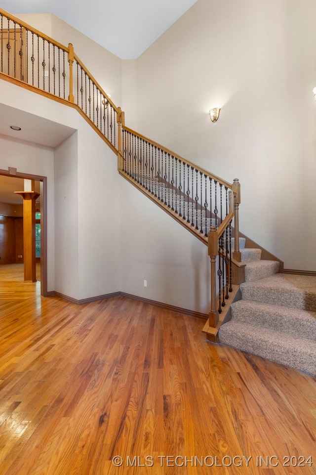 staircase featuring a towering ceiling and hardwood / wood-style floors