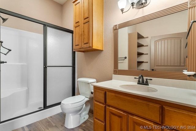 bathroom featuring hardwood / wood-style floors, a shower with door, vanity, and toilet