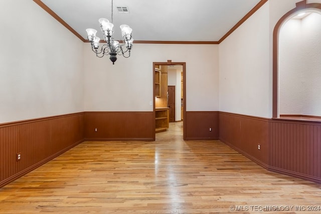 empty room featuring crown molding, light hardwood / wood-style flooring, and a notable chandelier