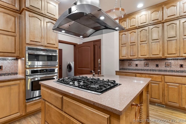 kitchen featuring island exhaust hood, light hardwood / wood-style flooring, stainless steel appliances, and tasteful backsplash