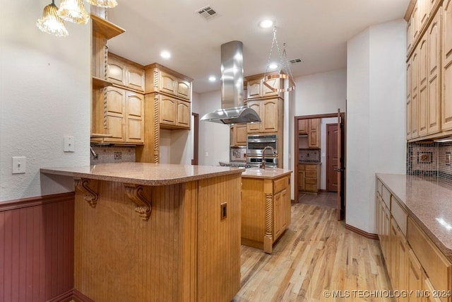 kitchen with island exhaust hood, backsplash, light hardwood / wood-style floors, and a kitchen island