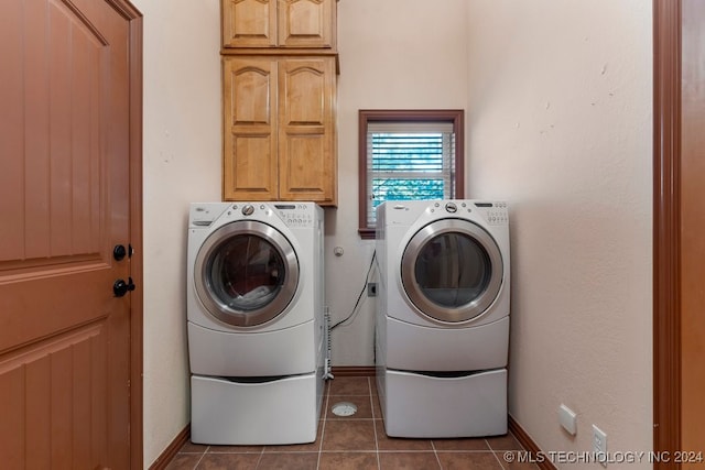 washroom with cabinets, dark tile patterned flooring, and washing machine and dryer