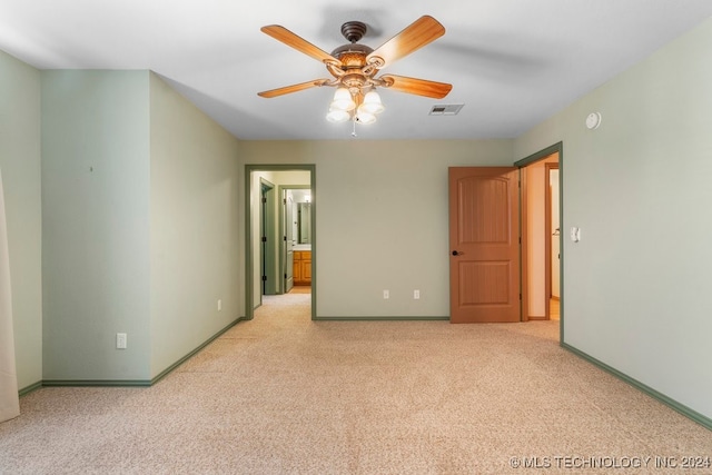 unfurnished bedroom featuring light carpet, ensuite bath, and ceiling fan