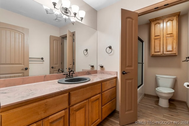 full bathroom featuring combined bath / shower with glass door, hardwood / wood-style flooring, vanity, and toilet