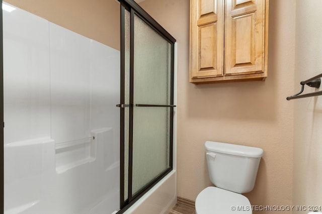 bathroom featuring bath / shower combo with glass door and toilet