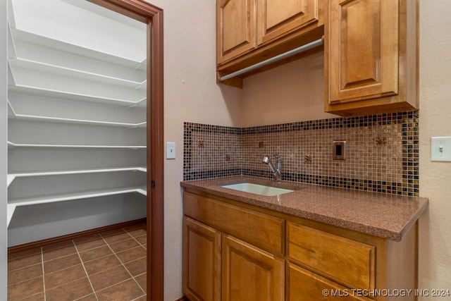 interior space featuring sink, dark tile patterned flooring, and tasteful backsplash